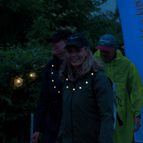 Lachende vrouw met pet en lichtgevende ketting.