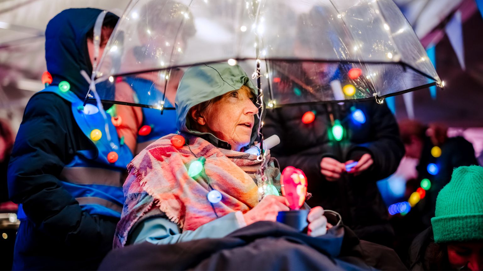 Drie wandelende vrouwen in de nacht met lichtslinger op de achtergrond.